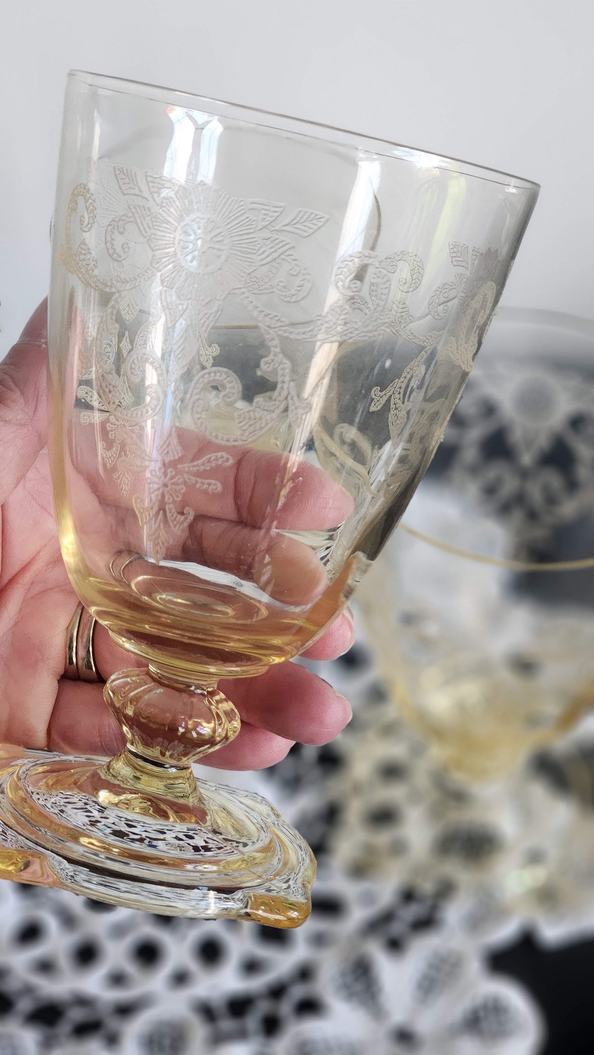 Close view of floral and scrolling etching, shaped stem, and square foot on a yellow glass tumbler