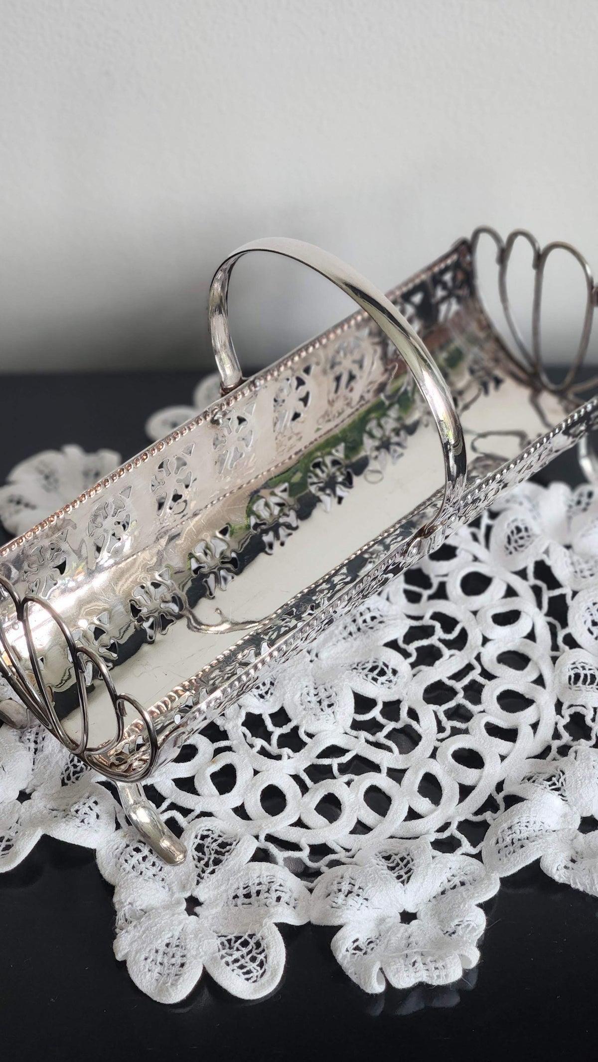Vintage silverplate cracker basket with pierced sides, arched center handle, wire fan ends, and decorative feet