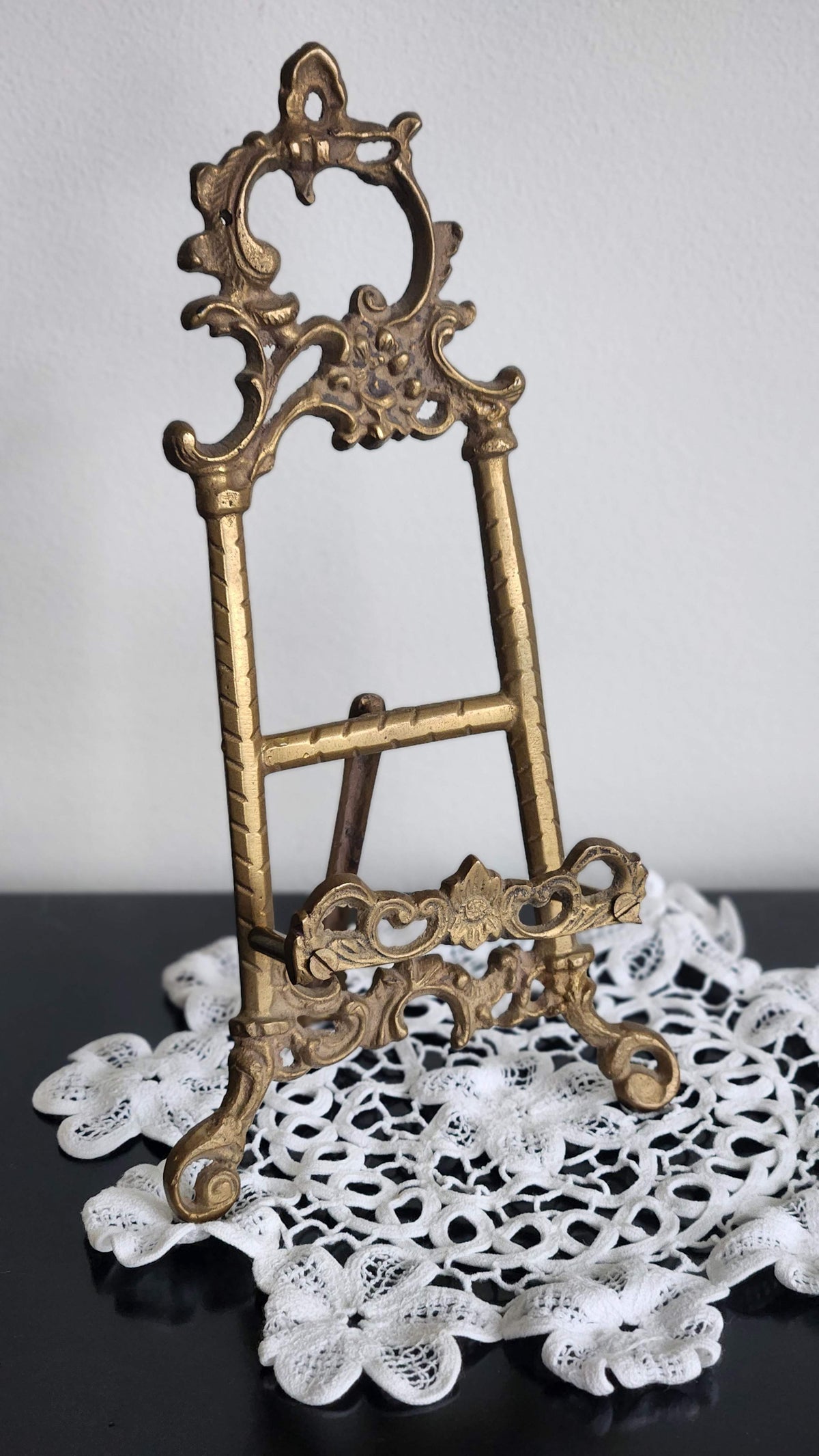 Front view of ornate vintage brass Rococo-style display easel with floral scrollwork and curved feet