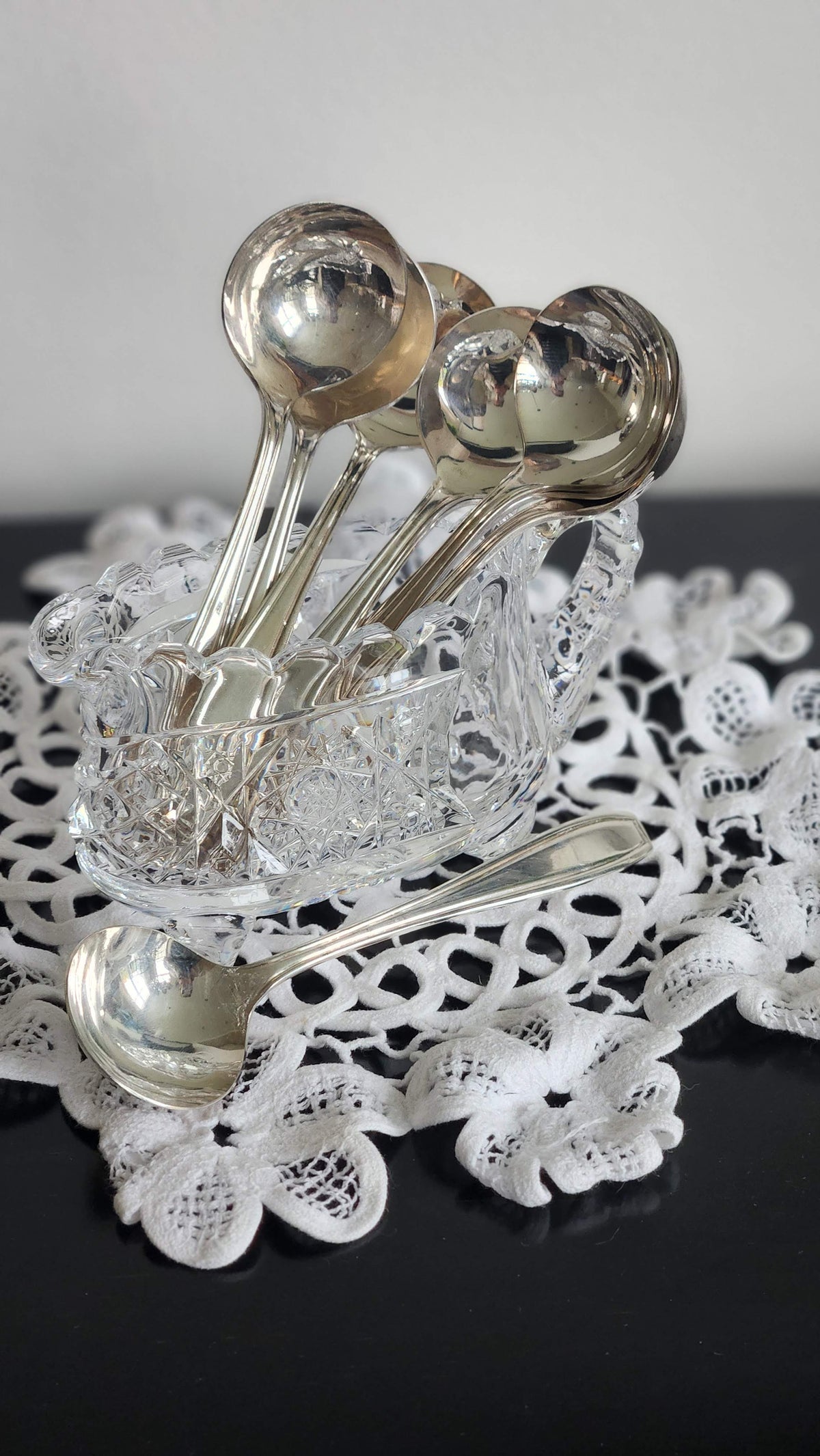 Vintage round-bowl bouillon spoons displayed in a glass holder with one spoon in front; holder not included