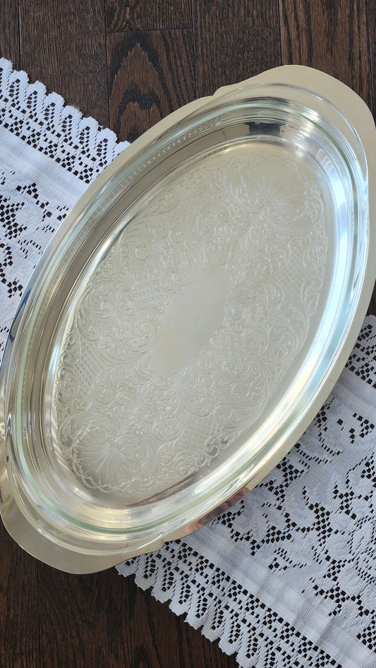 Oval silverplate casserole server with clear glass insert and chased scroll decoration