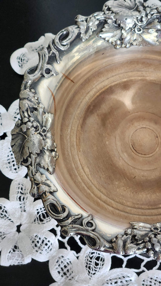 Vintage silverplate wine bottle coaster with ornate grapevine rim and turned wood base